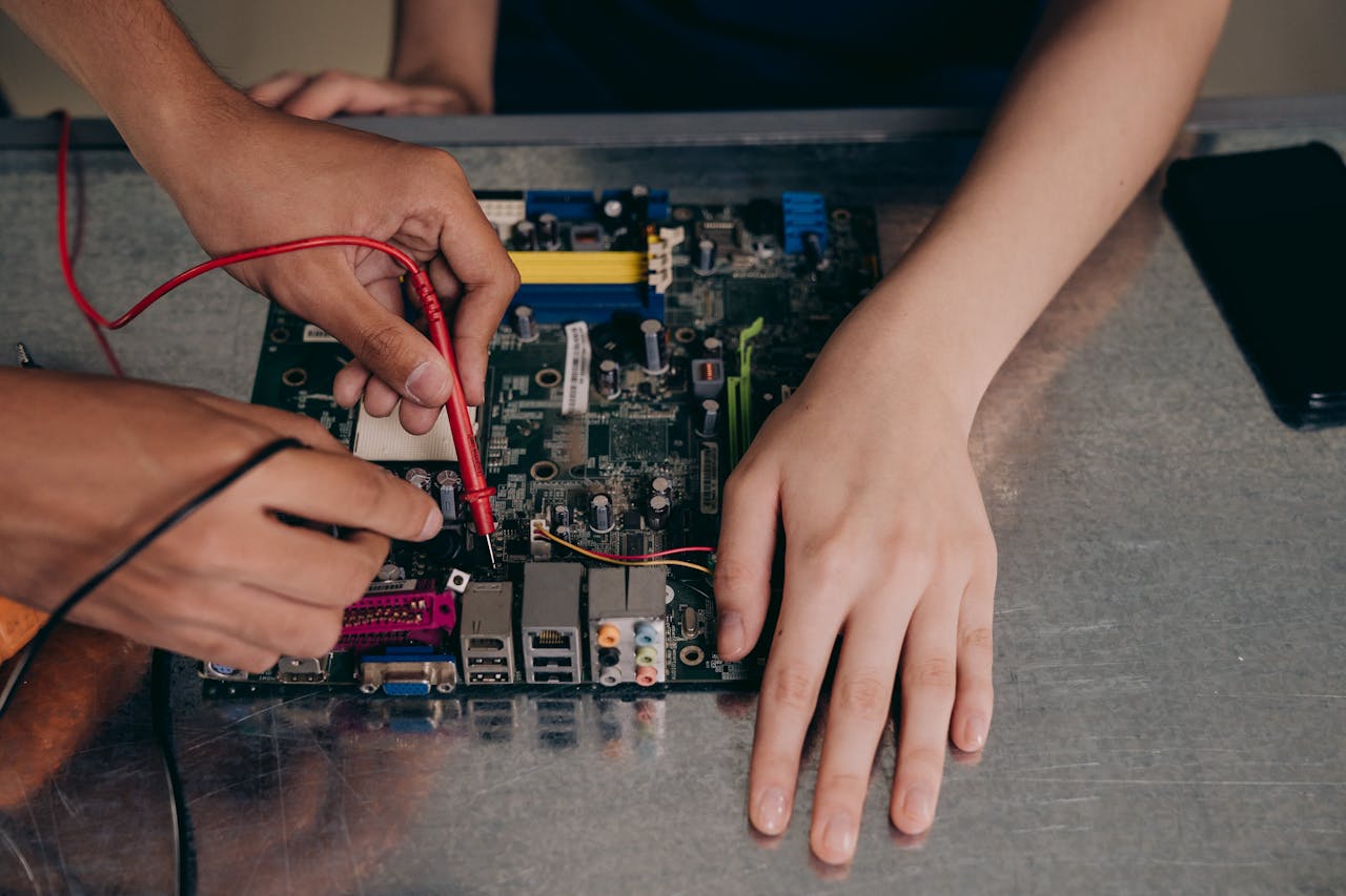 Hands working with electrical tester on motherboard, showcasing technical repair skills.